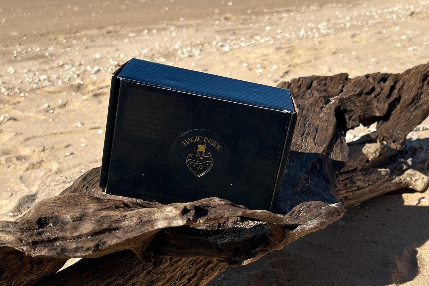 Black box with a magic inside sticker on a piece of driftwood on a sandy beach