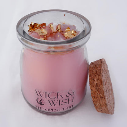 The Open Heart candle in a glass jar with gold flakes and a cork lid on a white background, branded 'Wick & Wish'.