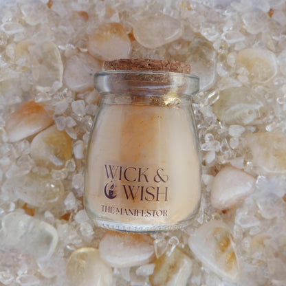The Manifestor candle labeled 'Wick & Wish' on a bed of citrine stones