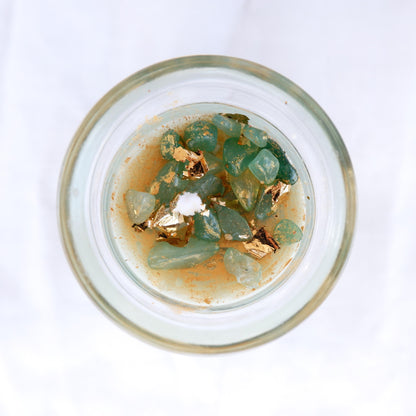 Top view of the Wick & Wish The Lucky one candle in a Glass container with green aventurine crystals and gold elements on a white background