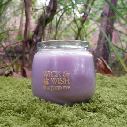 Purple candle with 'Wick & Wish' branding in a forest setting