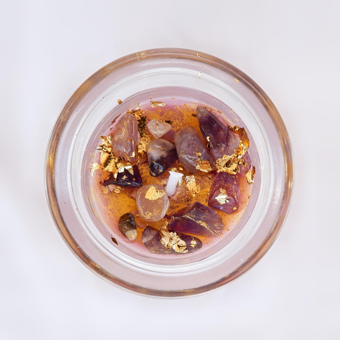 The Third Eye candle in a Glass container with purple amethyst stones and gold foil on a white background