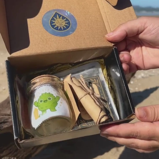 Golden Moonling packaging showcased on the beach with a glass jar, sticker, scroll shown