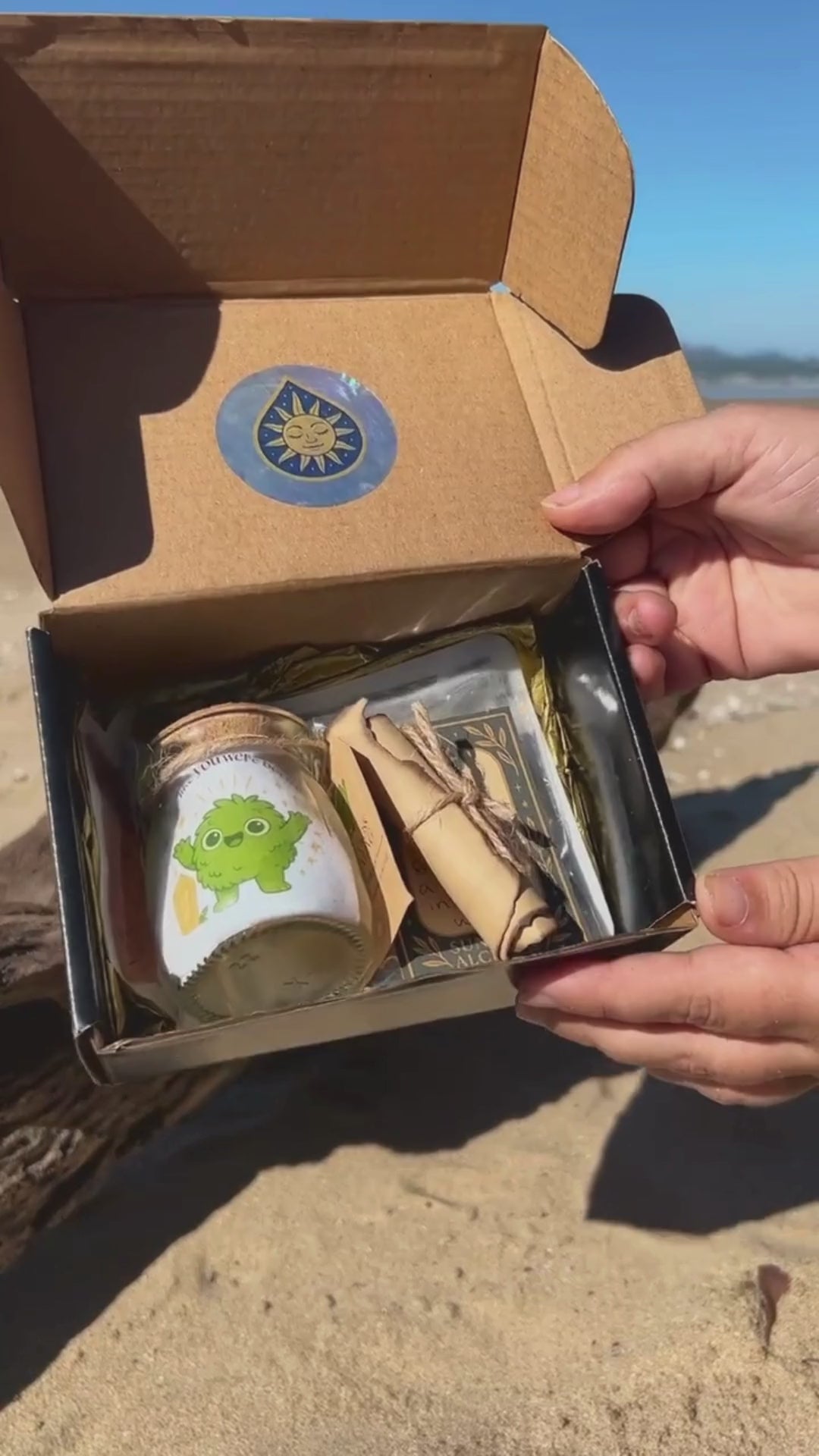 Golden Moonling packaging showcased on the beach with a glass jar, sticker, scroll shown